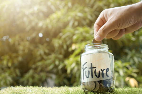 Hand placing a coin into a jar labelled "Future," representing superannuation savings and planning for when you can access your super in retirement.